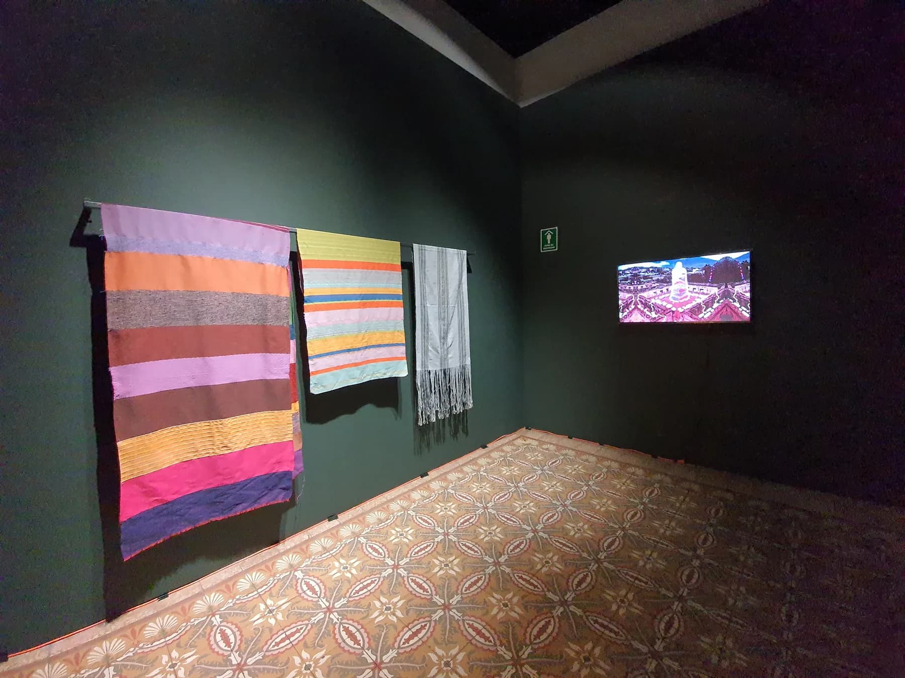 Vista panorámica de la exposición Mexifuturismos, con textiles suspendidos y una pieza audiovisual