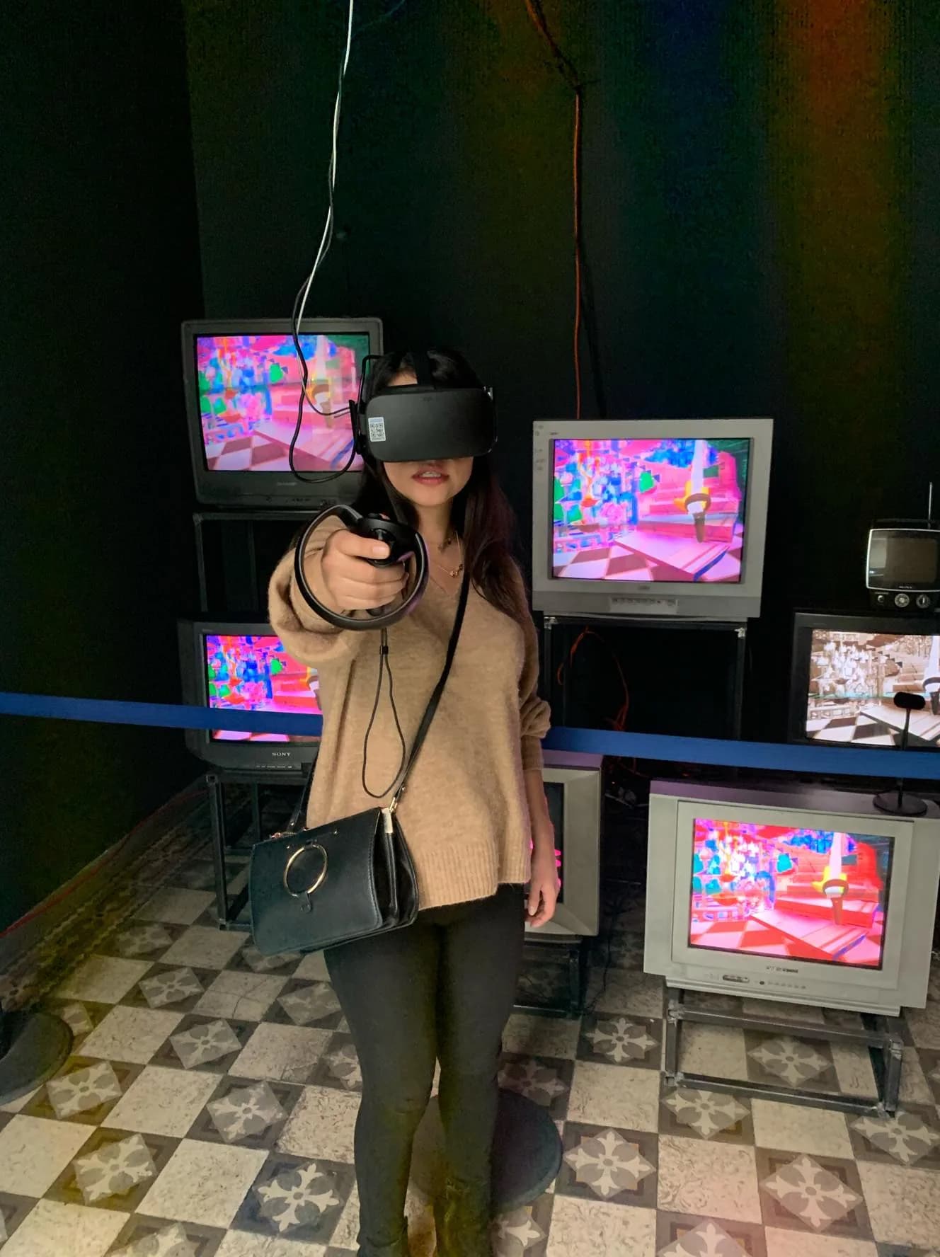 Visitante usando un visor de realidad virtual frente a una instalación de pantallas de colores