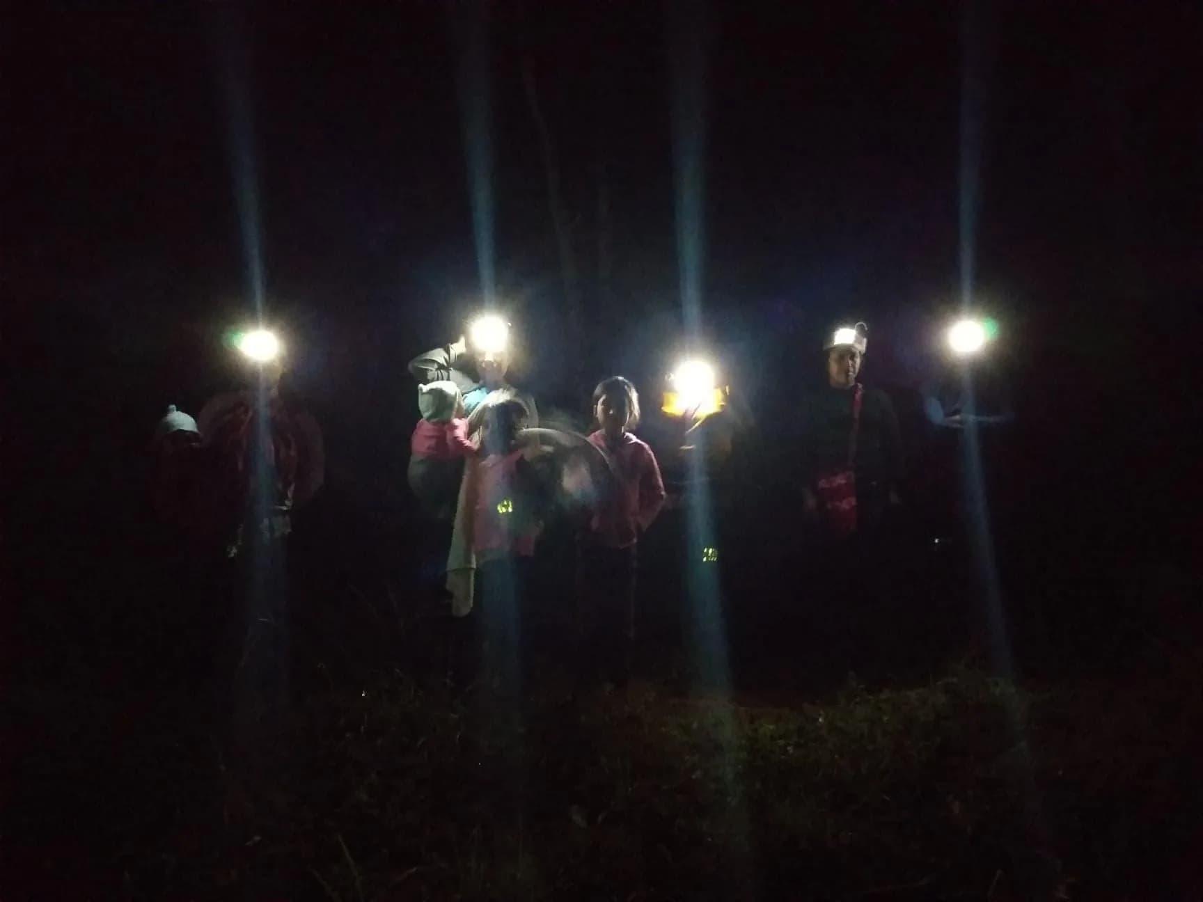 Grupo caminando de noche mientras ilumina el sendero con bandas de luz tejidas