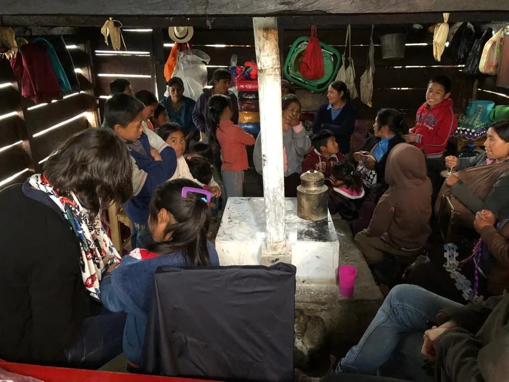 Familia, estudiantes y docentes reunidos alrededor del fogón en la Casa de la Partera